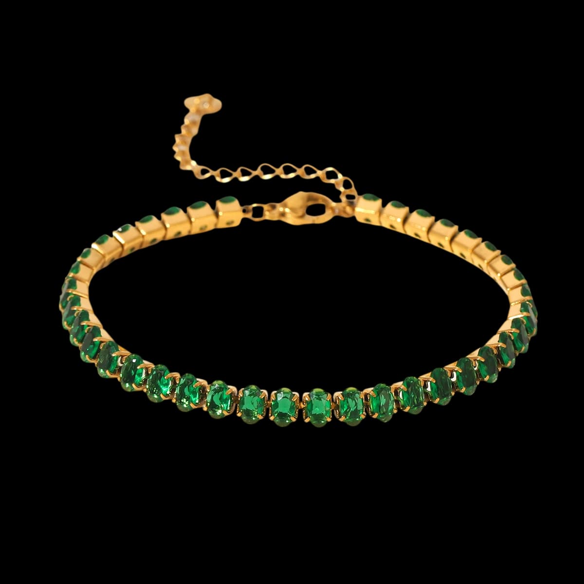 A golden-tone bracelet with a row of oval green stones and an extension chain.